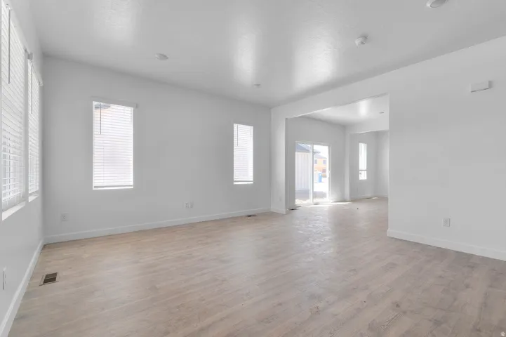 Bright interior space with light wood-finish flooring, white walls, and multiple windows