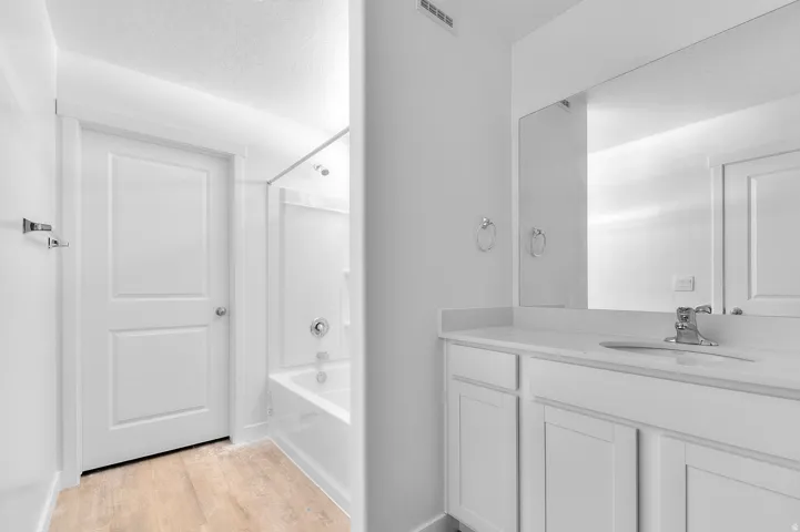 Modern bathroom with white vanity cabinetry, light countertop, and chrome fixtures