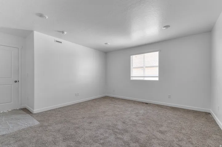 Carpeted room featuring a double-pane window with horizontal blinds, recessed lighting, and a white interior door
