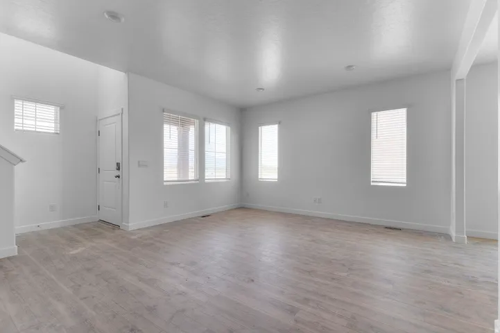 Spacious interior featuring light wood-finish flooring, recessed lighting, multiple windows with blinds, and white trim