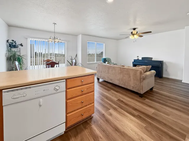 Open-concept living space featuring wood-finish flooring, a kitchen island with integrated dishwasher, a sliding glass door, and recessed lighting
