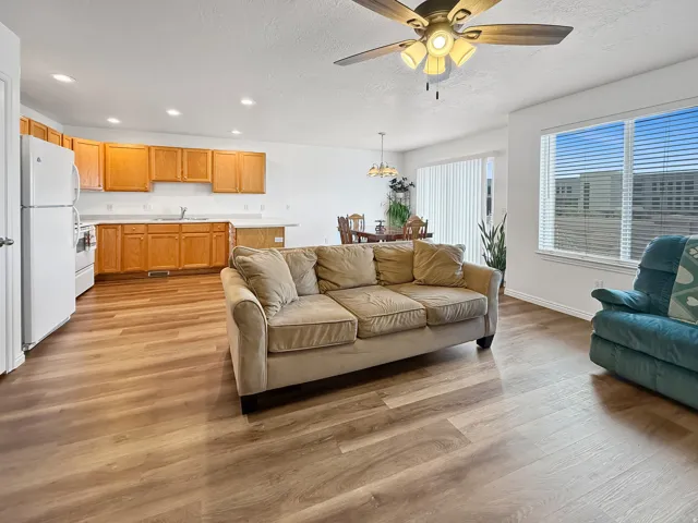 Open-concept living space featuring wood-finish flooring, white walls, and a ceiling fan
