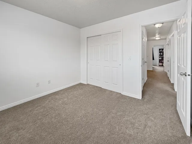 Neutral-toned carpeting extends throughout the room and into the hallway
