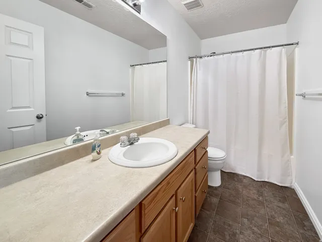 Bathroom featuring a wood-finish vanity with an integrated sink and a light-toned countertop