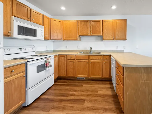 Kitchen featuring wood-finish cabinetry, light-toned countertops, and wood-finish flooring