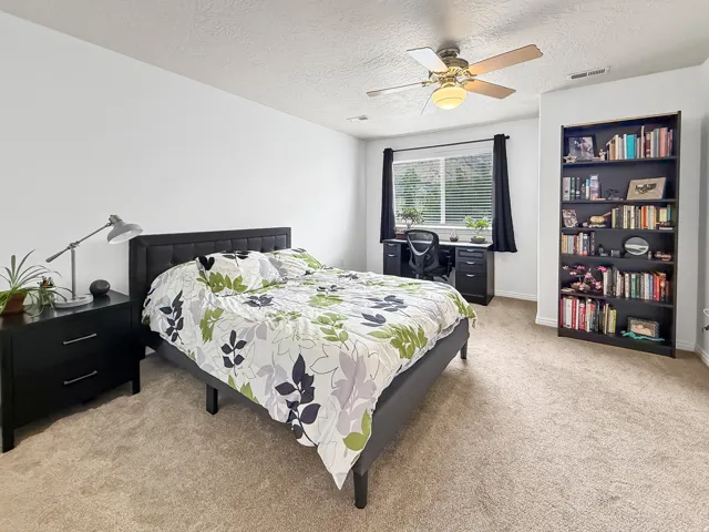 Carpeted bedroom featuring a window with blinds, a ceiling fan, and white walls