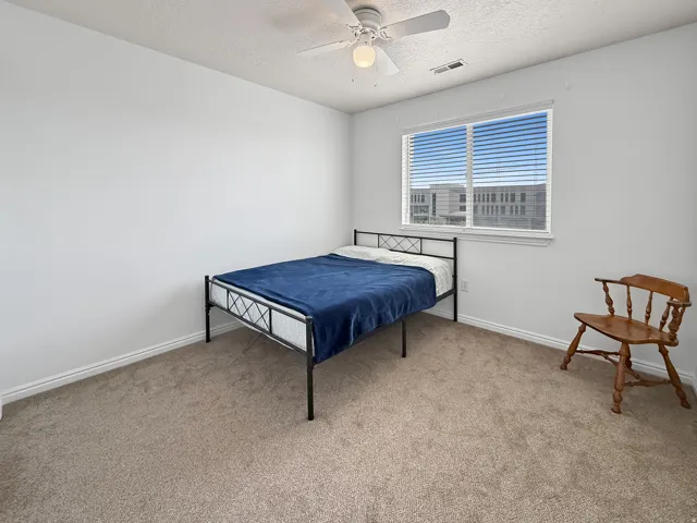 Carpeted room featuring a ceiling fan with integrated lighting, white baseboards, and a window with horizontal blinds