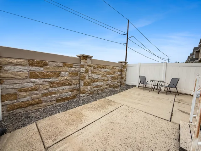 Outdoor patio area featuring a stone veneer wall with cap, a gravel border, and a concrete pad