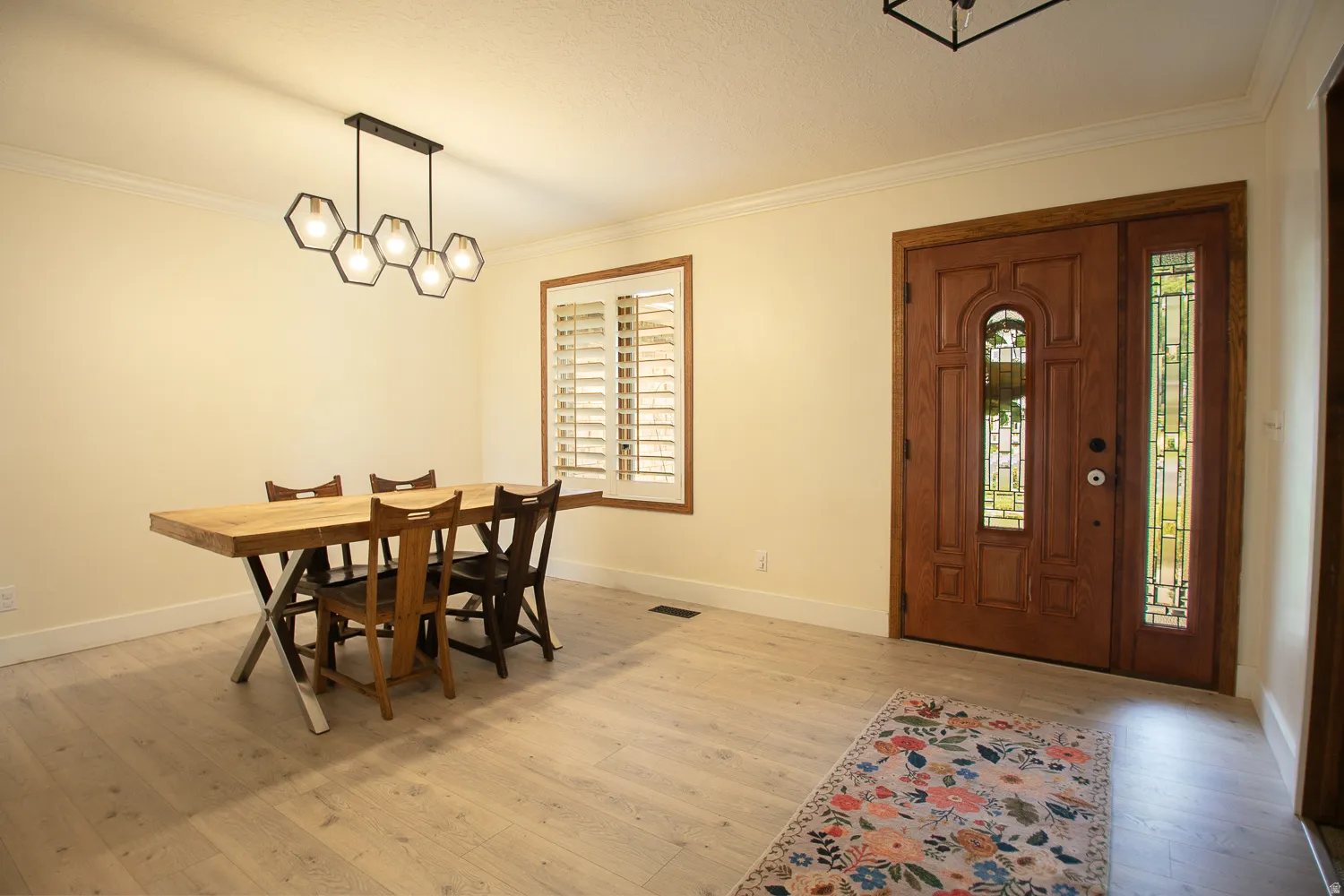 Light wood-finish flooring complements the crown molding and baseboards