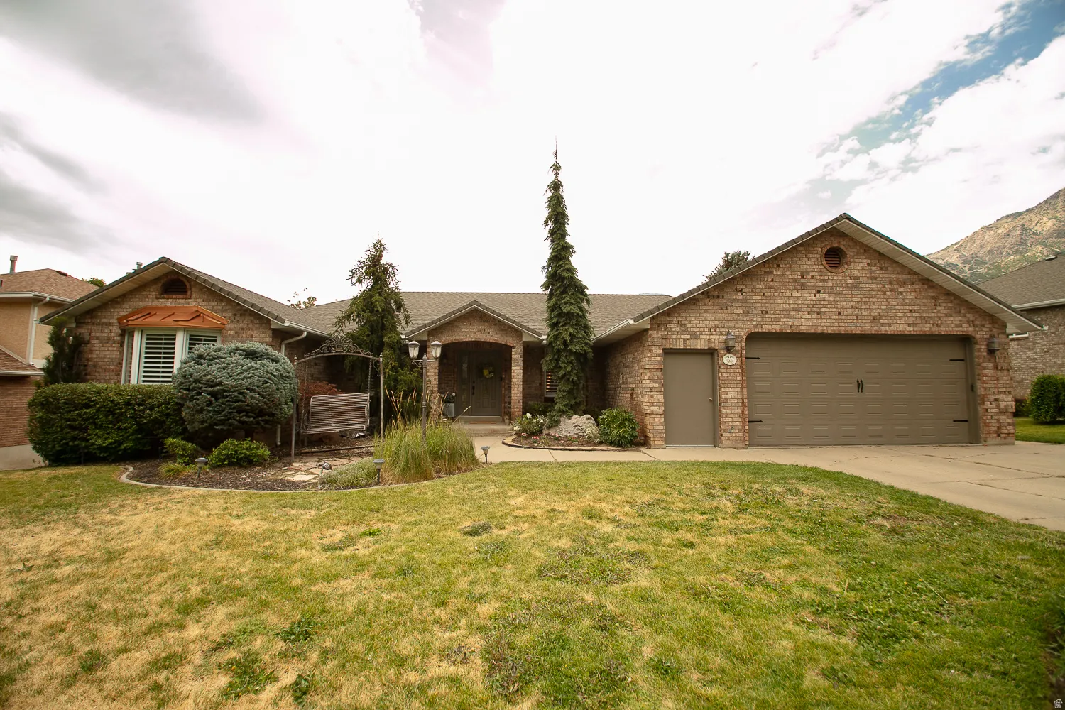 Brick exterior featuring an attached two-car garage with a brown door