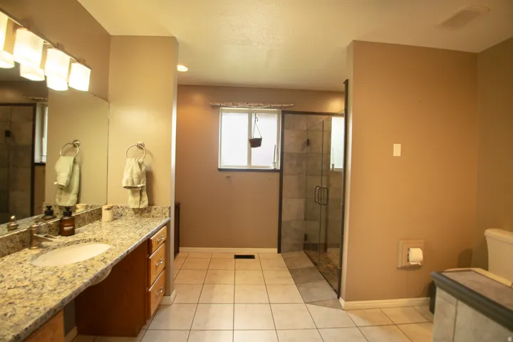 Bathroom featuring a granite-topped vanity with an undermount sink, a large wall mirror, and a multi-light fixture