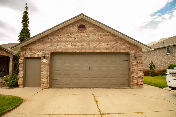 Brick exterior featuring a two-car garage with an additional side entry door