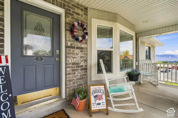 Covered porch entrance with a decorative glass-paneled door, bay windows, and brick facade