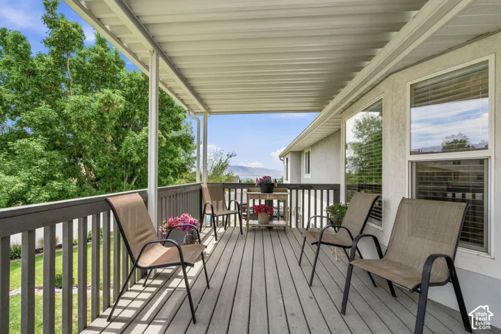 Covered outdoor deck with wood-finish flooring, white overhead ceiling, and dark-stained railing