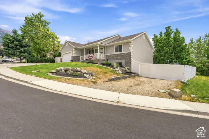Contemporary split-level residence featuring a gray exterior with stone accents and a covered front porch