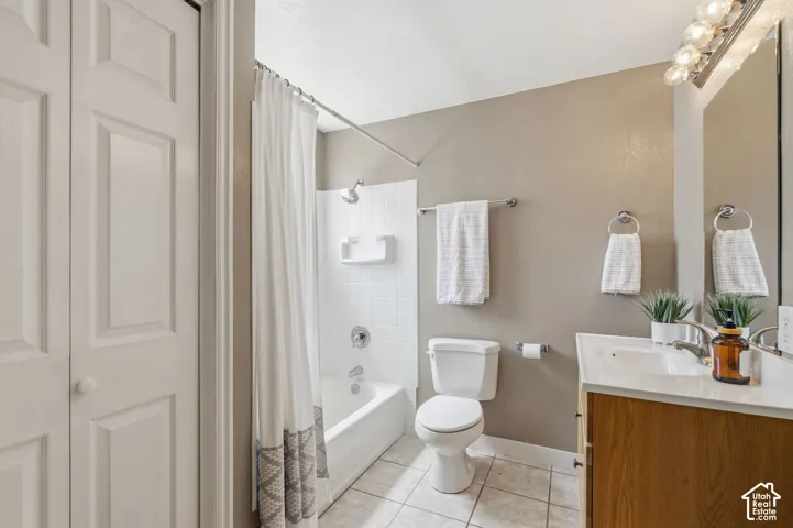 Full bathroom featuring a white porcelain tub with subway tile surround, tile flooring, a wood-finish vanity with an integrated sink, and an overhead vanity light fixture