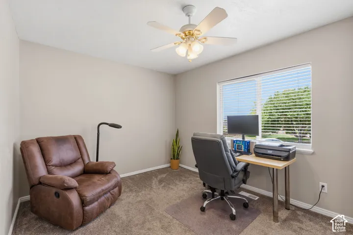 Carpeted room featuring a ceiling fan with light fixture, neutral wall paint, and a window with blinds