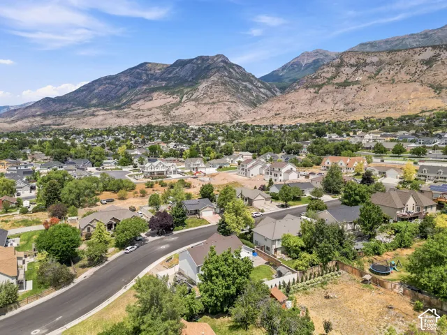 Mountainous terrain surrounding a residential area featuring established homes, new construction, mature trees, and paved streets