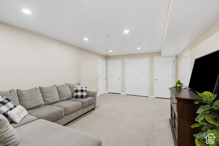 Spacious room featuring neutral carpeting, recessed lighting, and multiple white panel doors