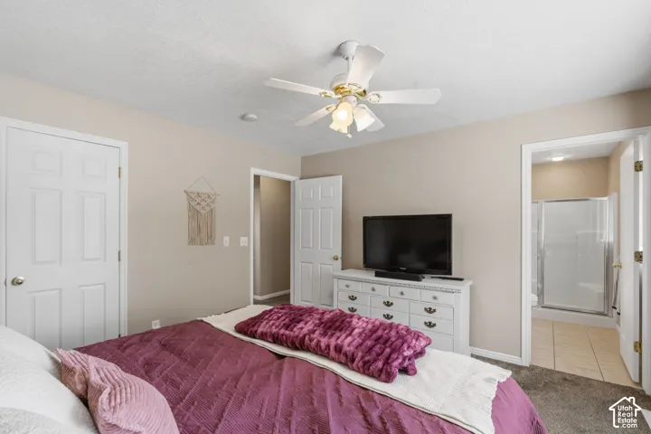 Bedroom featuring neutral wall color, carpet flooring, a ceiling fan with integrated lighting, and a doorway opening to a bathroom with tile flooring and a shower enclosure