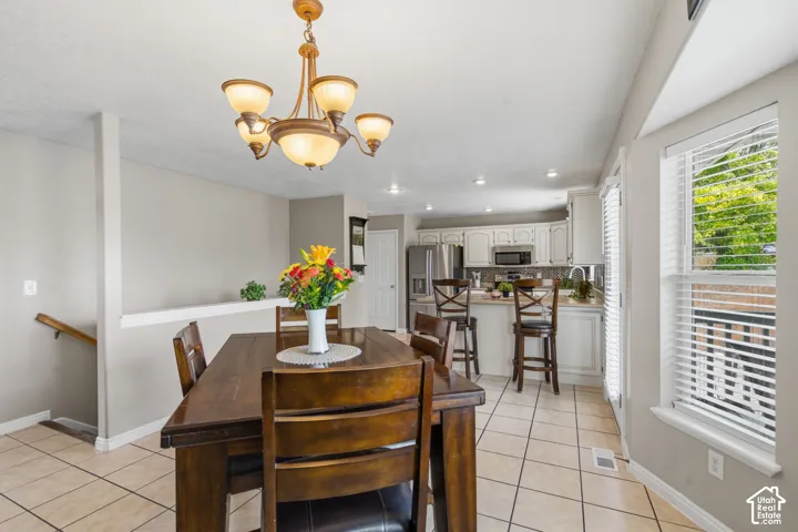 Dining area featuring a wood-finish table, overhead chandelier, and ceramic tile flooring