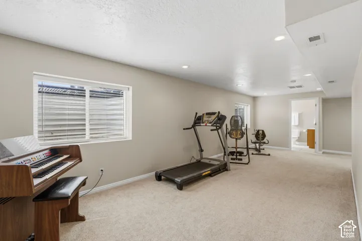 Carpeted recreation area with light-colored walls and a window featuring horizontal blinds