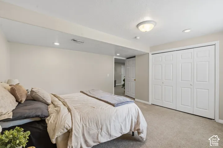 Carpeted room featuring a ceiling-mounted light fixture, recessed lighting, and a bi-fold closet with panel doors