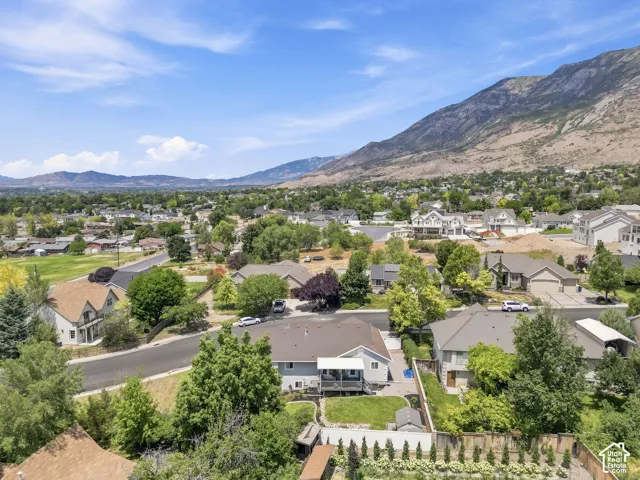 Residential neighborhood featuring diverse architectural styles and mature landscaping against a backdrop of mountains and distant hills