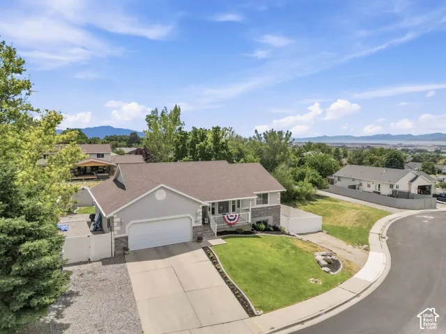 Stucco and stone exterior with an attached garage, paved driveway, and established front lawn