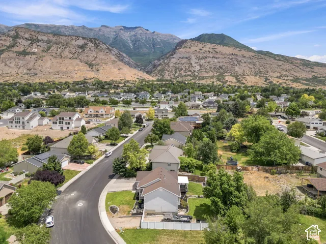 Residential neighborhood featuring paved roads, established homes, and mature trees, set against a backdrop of distant mountains