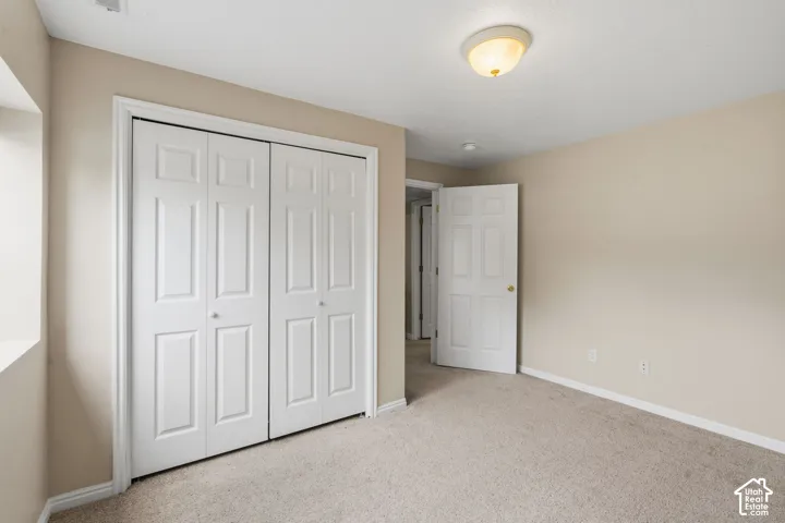 Neutral tone wall paint with white trim, light-colored carpeting, and a flush mount ceiling light fixture