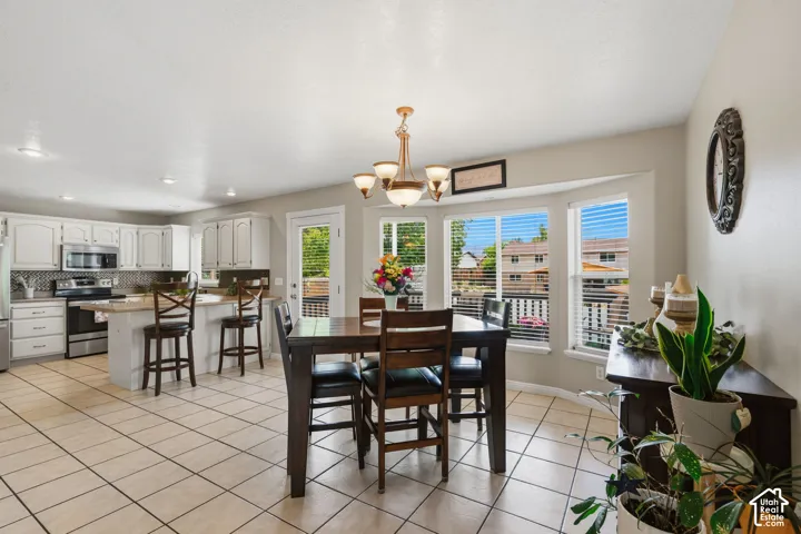 Open-concept kitchen and dining area featuring tile flooring, white cabinetry, and stainless steel appliances