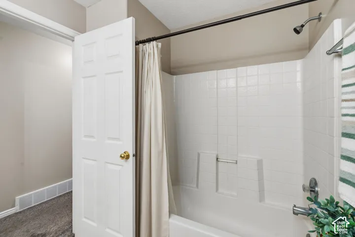 White shower and tub combination featuring a chrome showerhead and faucet