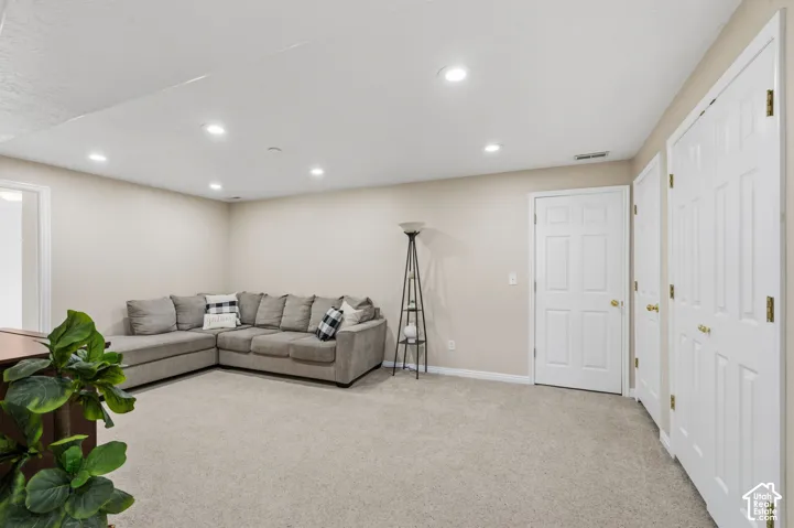 Recessed ceiling lighting illuminates the carpeted flooring and neutral wall tones