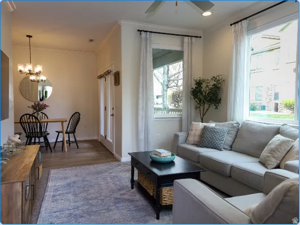 Open concept living area with wood-finish flooring, crown molding, and abundant natural light from multiple windows