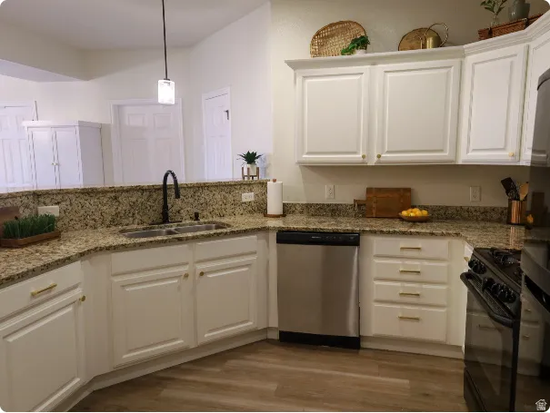 Kitchen featuring granite countertops, white cabinetry with gold-tone hardware, wood-finish flooring, a stainless steel dishwasher, and a black gas range
