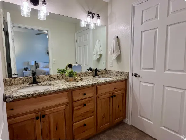 Double vanity with wood-finish cabinetry, black hardware, and granite-style countertops