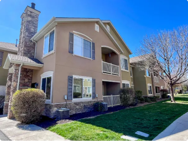 Multi-story exterior featuring a stone-clad chimney, stucco siding, and decorative window shutters