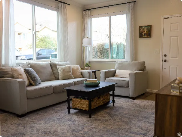 Living area featuring neutral wall paint, two large windows with white trim, and light-colored window treatments