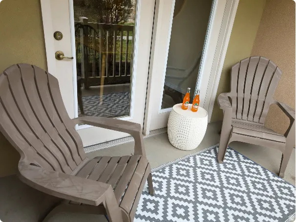 Outdoor patio space featuring double French doors with brass hardware, a geometric pattern rug, and a textured exterior wall finish