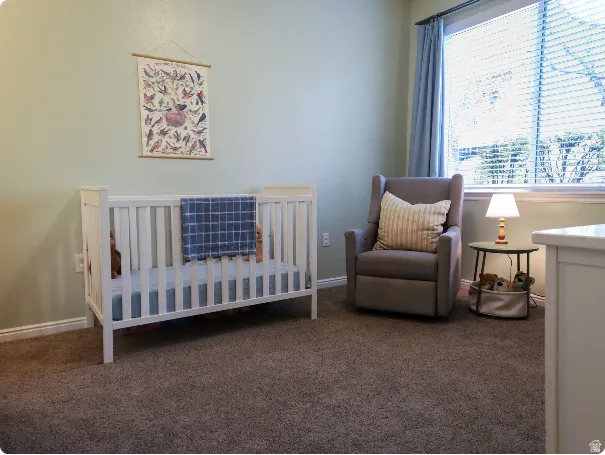 Spacious room featuring textured carpet flooring, light green wall paint, and white baseboards