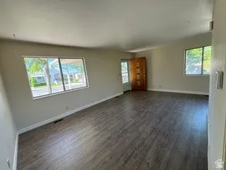 Spacious room with wood-finish flooring, light-toned walls, and multiple windows