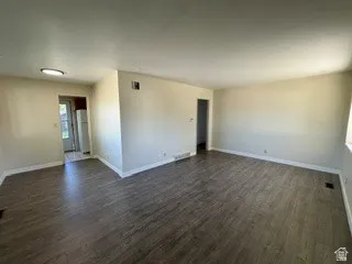 Open-concept living space featuring wood-finish flooring, neutral wall tones, and white baseboards