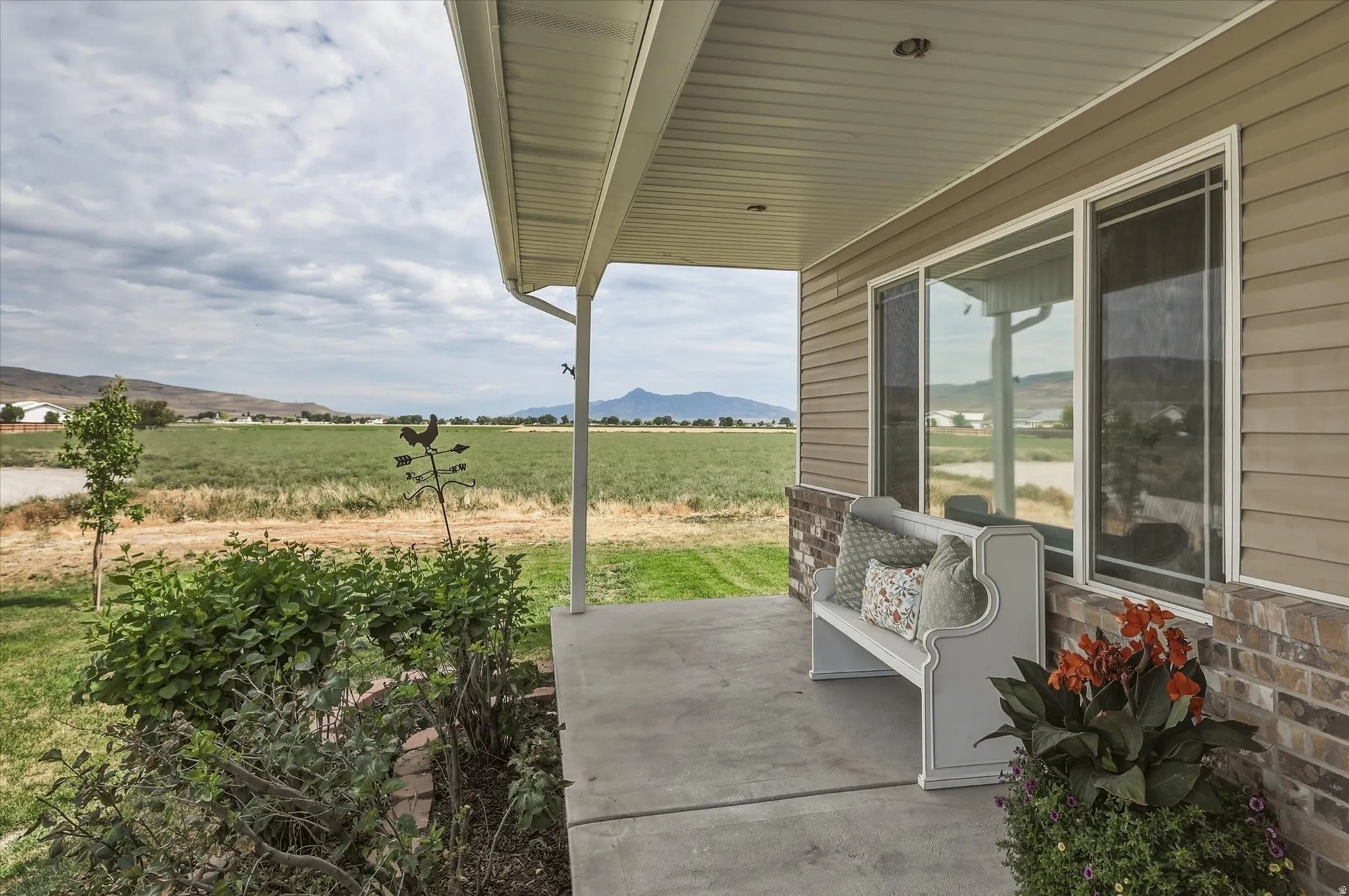 Covered front porch with concrete slab, flanked by a brick veneer base and horizontal siding