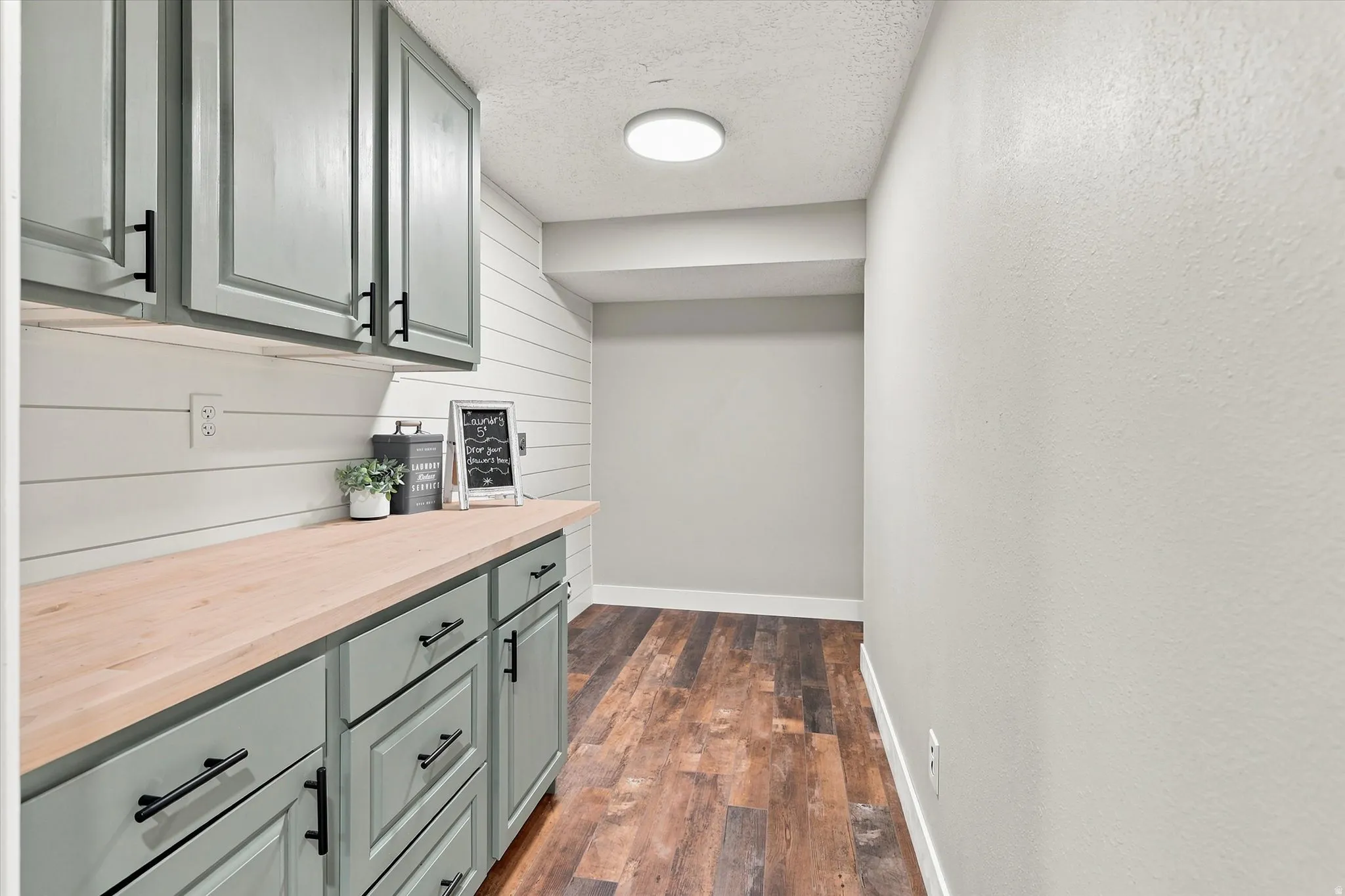 Extended countertop with custom cabinetry featuring matte black hardware, under-cabinet lighting, and shiplap-style backsplash