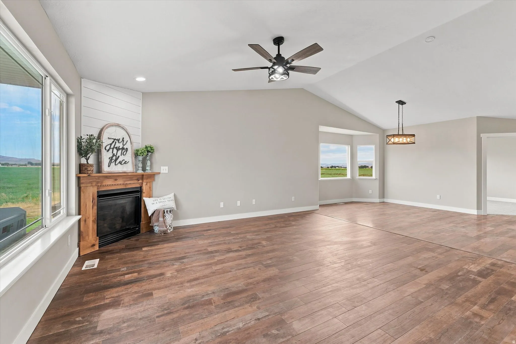 Spacious interior featuring wood-finish flooring, vaulted ceilings, and a fireplace with a shiplap accent wall