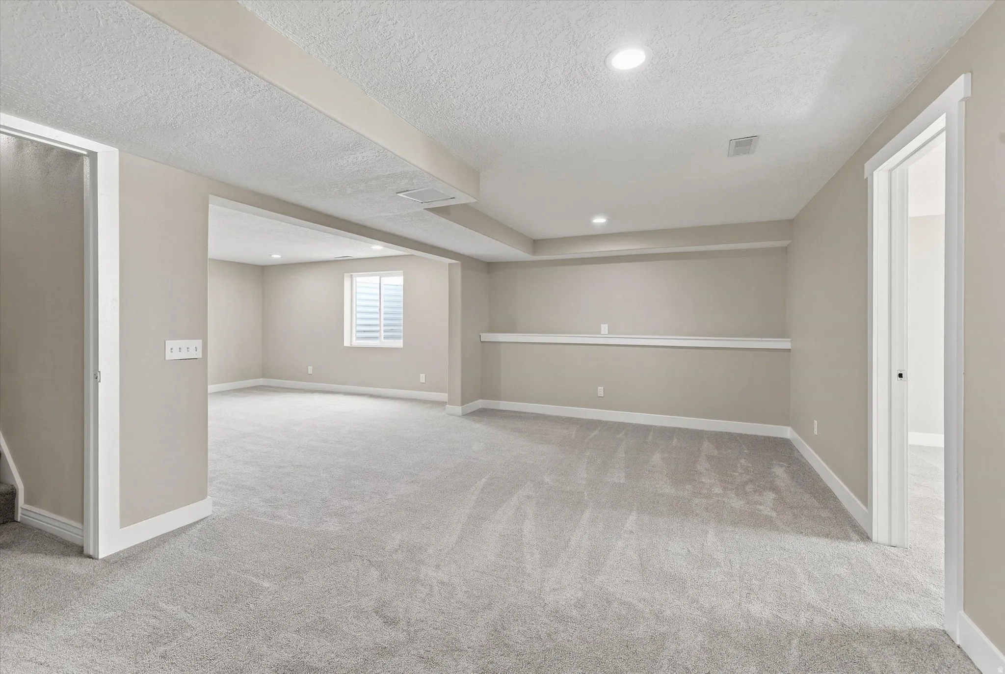 Spacious lower level featuring light gray carpeting, recessed lighting, neutral wall tones, and white trim