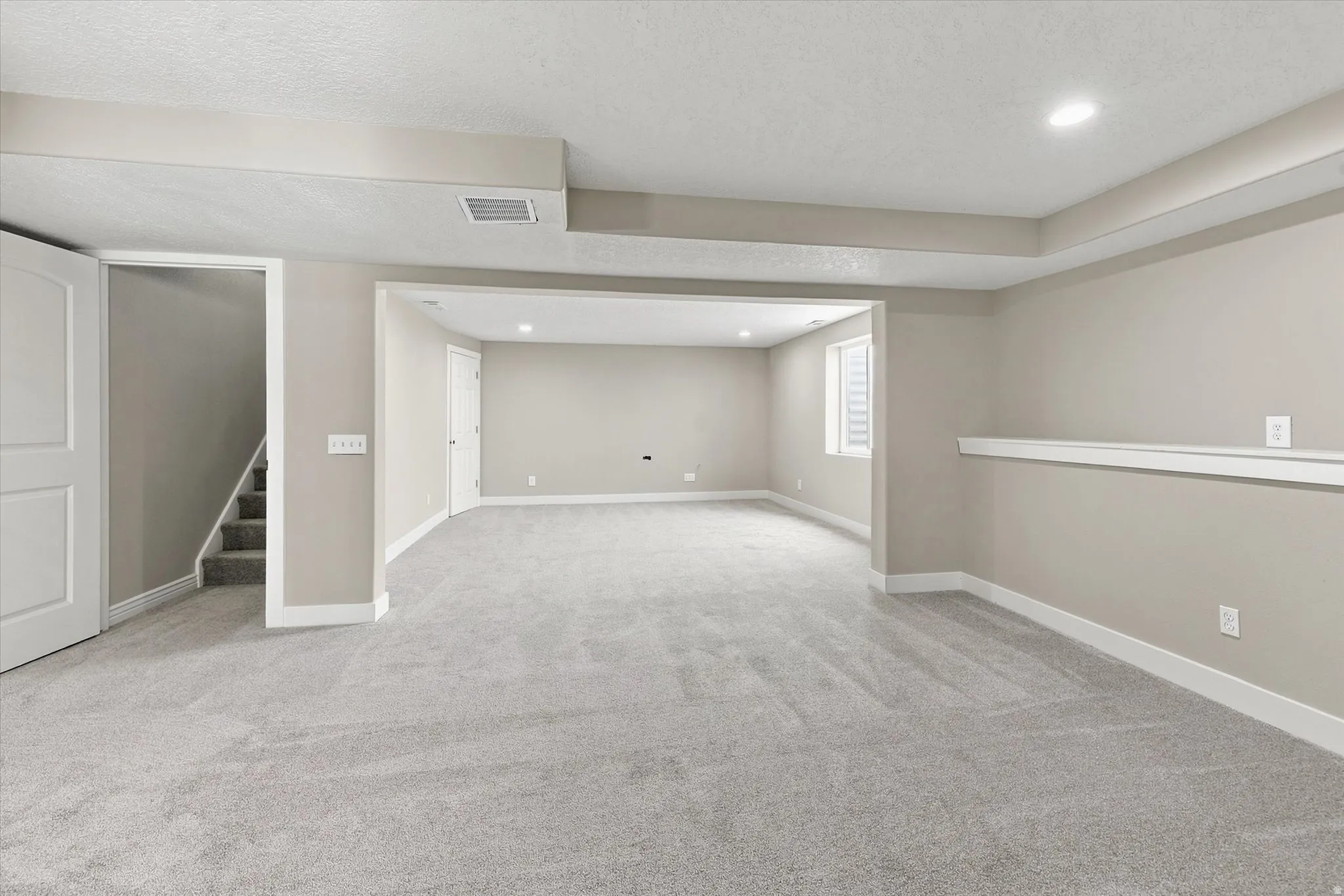Spacious carpeted room featuring recessed lighting and a window with blinds