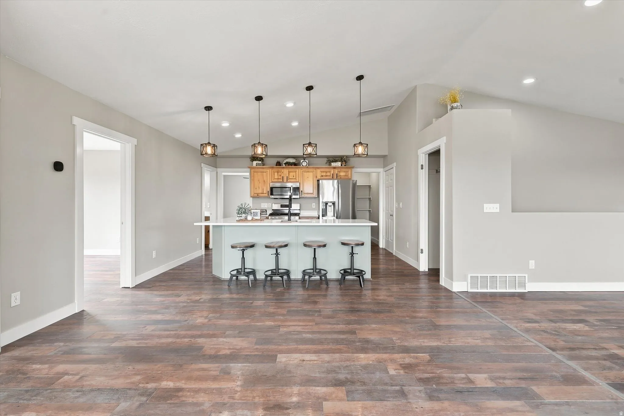 Spacious living area featuring wood-finish flooring, vaulted ceilings, and recessed lighting