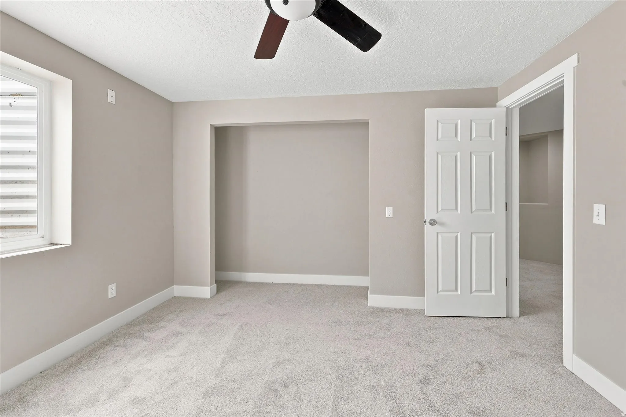 Carpeted room with neutral wall tones and white baseboards